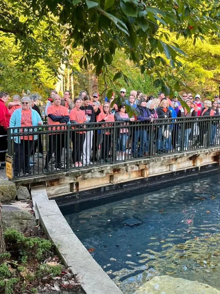 the chorus posing on the bridge at creekside gahanna to perform the national anthem before the spooky shuffle